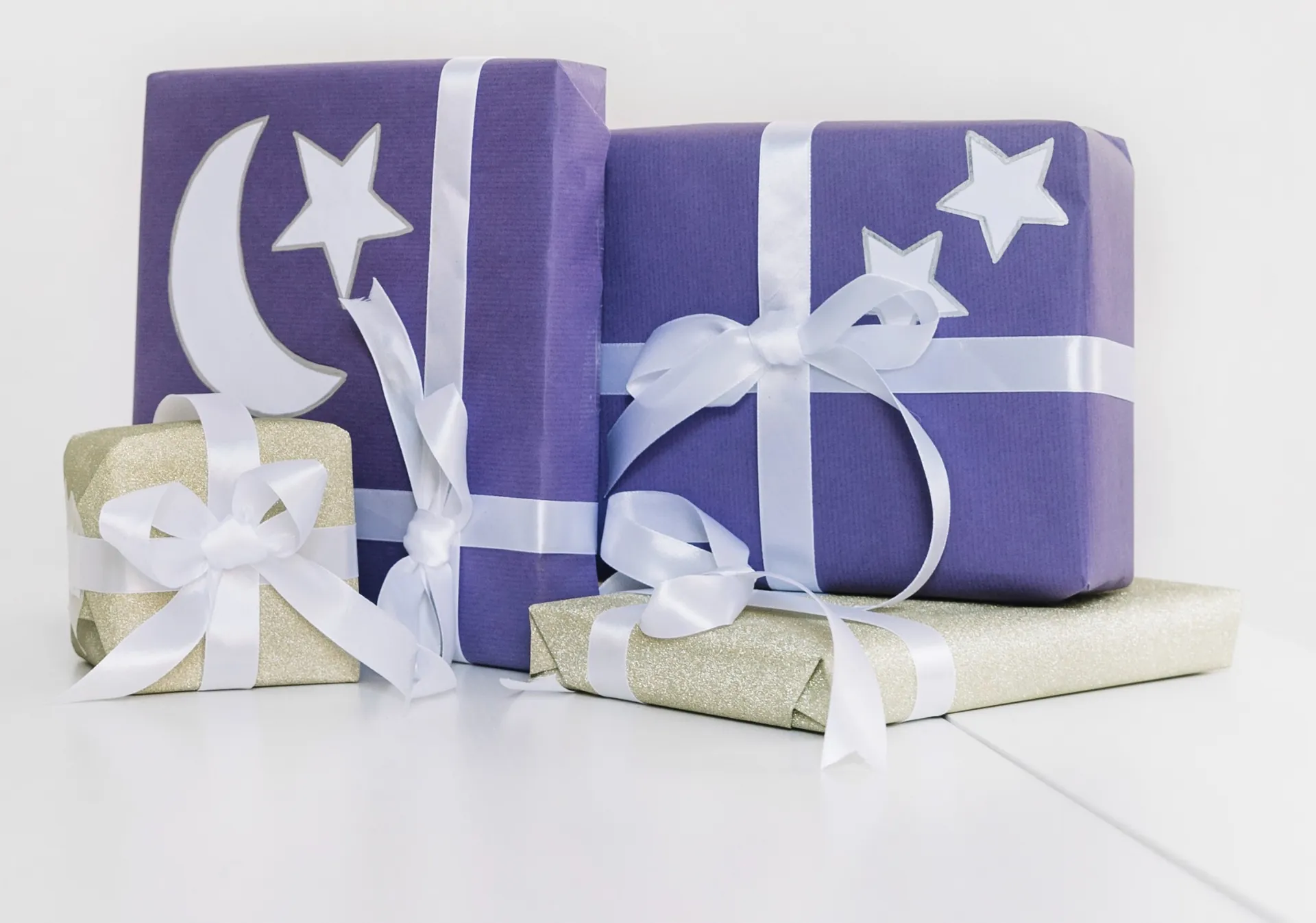 Elegant purple and gold Eid gift boxes with crescent and stars